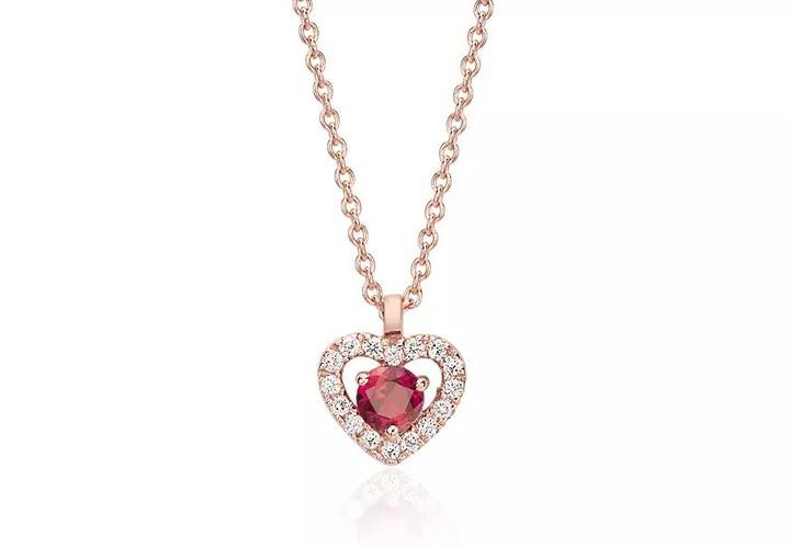 A heart-shaped pendant with round ruby center surrounded by diamond pavé in rose gold